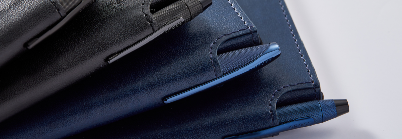 Midnight Blue and Classic Black journals with Cross pens secured in the journals’ pen slots, displayed side by side.