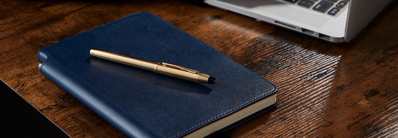 23KT Gold-Plated Century II Pen resting on a Midnight Blue journal.