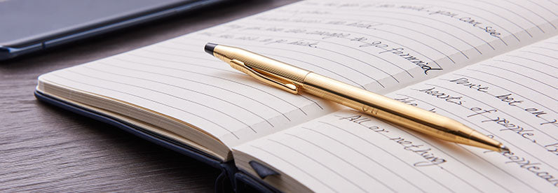 Classic Century 23KT Gold-Plated Ballpoint Pen resting on an open journal.