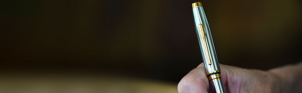 Hand writing with the Coventry Medalist Ballpoint Pen, featuring a polished chrome finish with gold-tone accents.