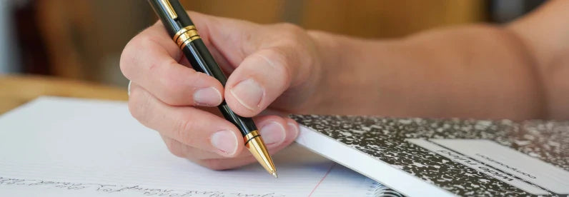 Close-up of hand writing with the Coventry Ballpoint Pen in Black Lacquer with Gold PVD appointments.
