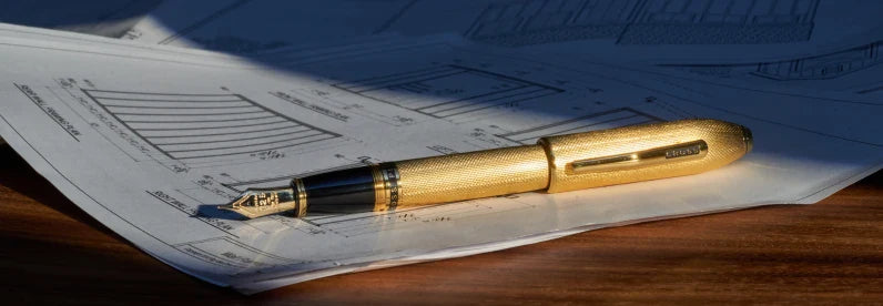 23KT Heavy Gold-Plated Peerless Fountain Pen resting on top of architectural blueprints.