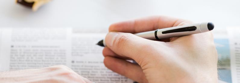 Man holding the Tech3+ Brushed Chrome Pen over a newspaper.
